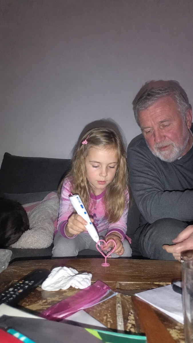Una bambina sorride mentre tiene la penna 3D Pen'Up e la sua creazione